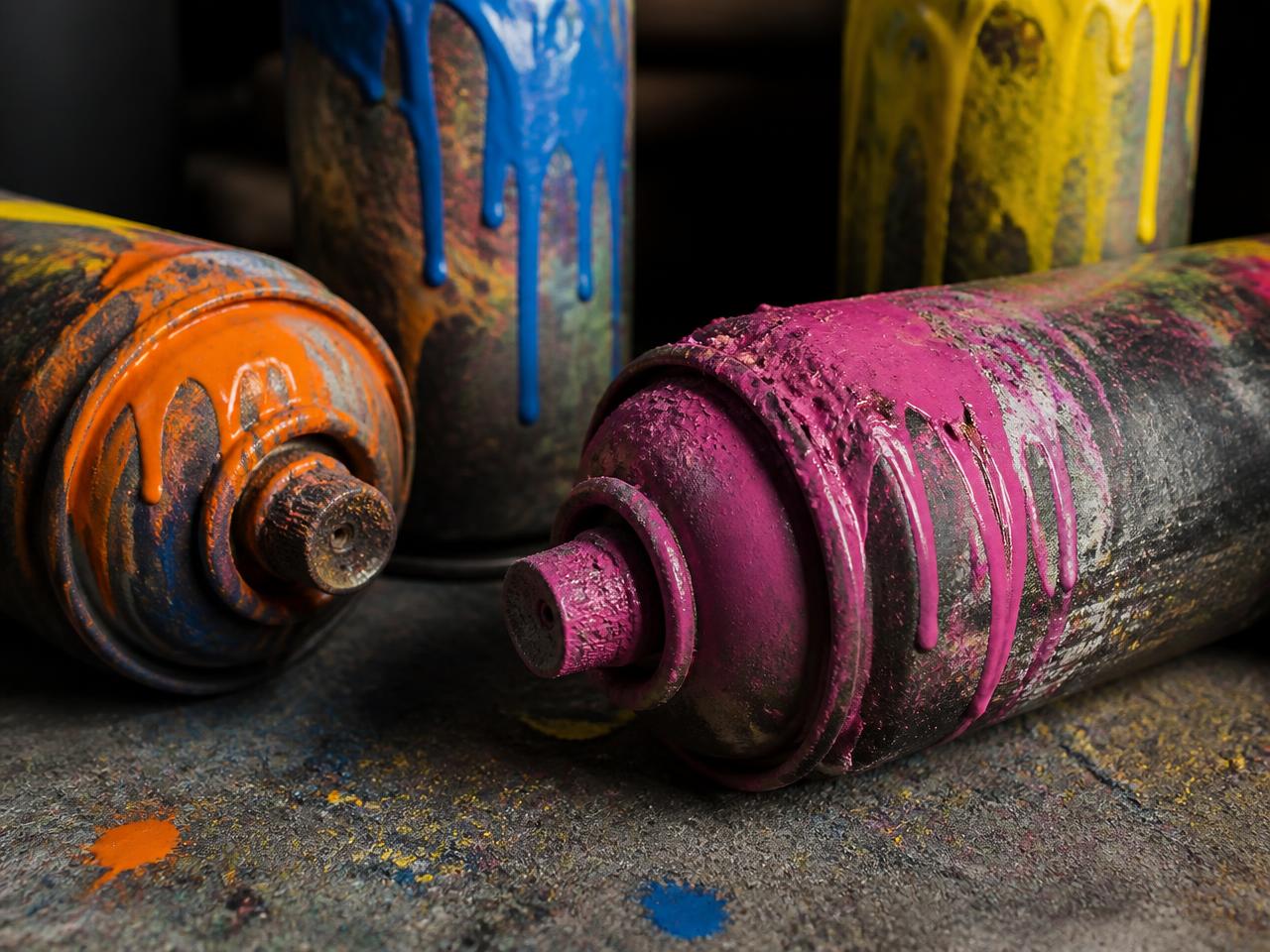 Close-up of paint-covered spray cans on a studio floor